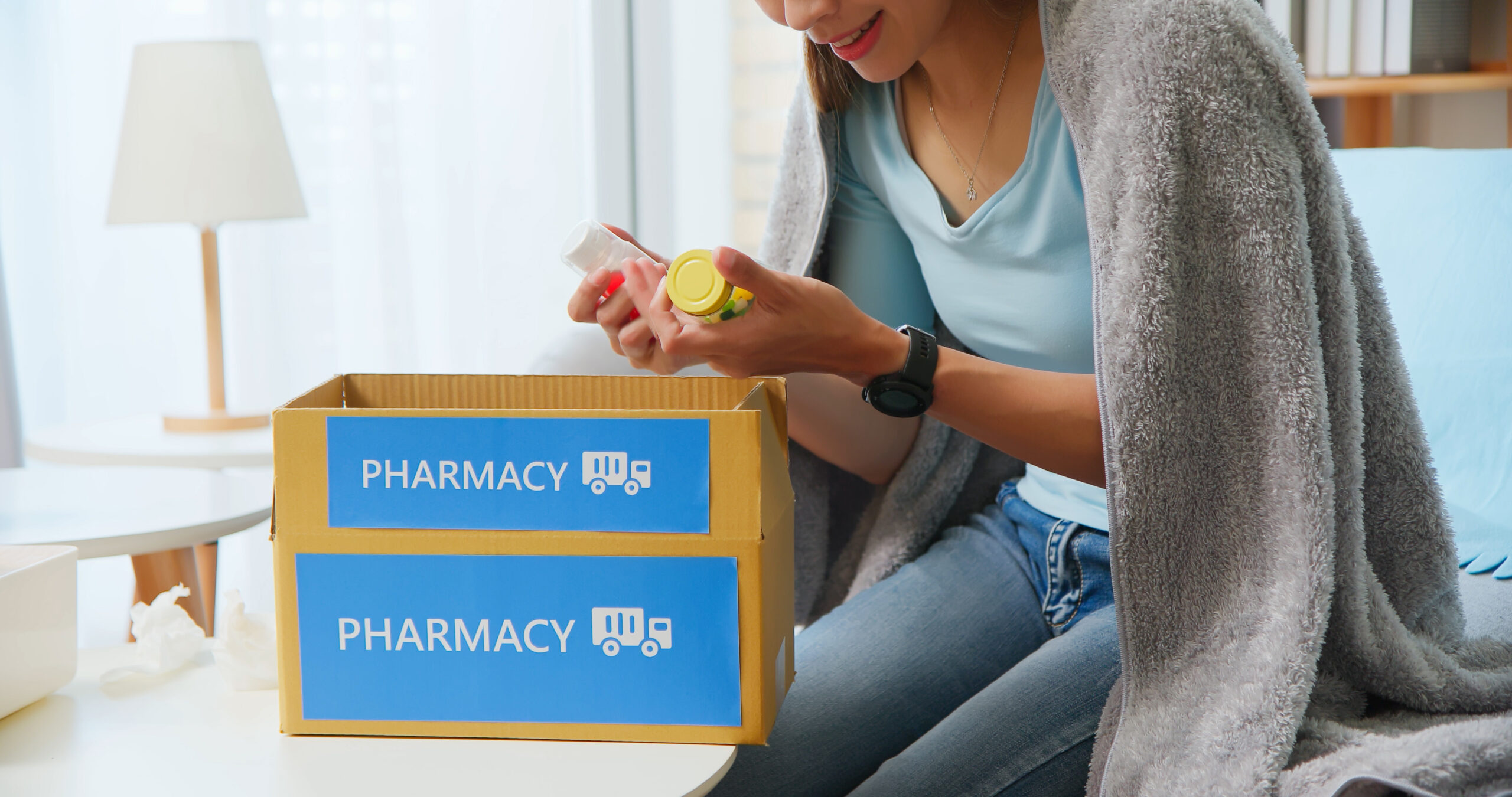 close up of asian female patient wear mask covering blanket unpacked medicine from pharmacy medication package box delivery service at home